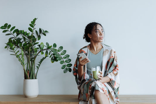 a pensive woman sitting down with a glass of matcha